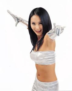 a woman in white is posing with her arms out and hands behind her head while wearing silver gloves