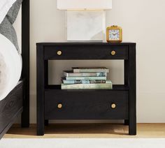 a night stand with books and a clock on it