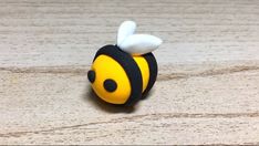 a small yellow and black toy with a bee on it's back end sitting on a wooden surface