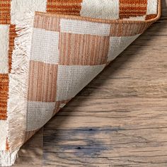 an orange and white checkered rug on top of a wooden floor