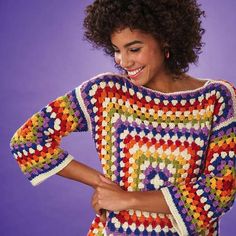 a woman wearing a multicolored crochet sweater and smiling at the camera