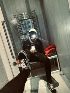 a man sitting in a shower with his feet up on the floor and wearing sneakers