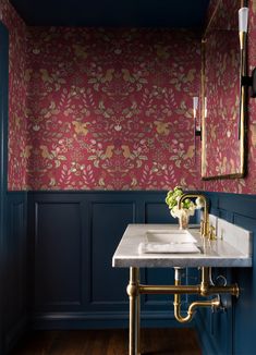 a bathroom with blue walls, gold fixtures and a marble sink in the middle of the room