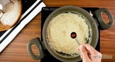 a person stirring food in a pot on top of a stove with a wooden spoon