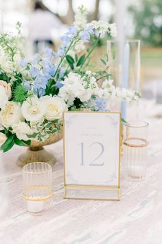 the table is set with flowers and candles for an elegant wedding reception in blue and white