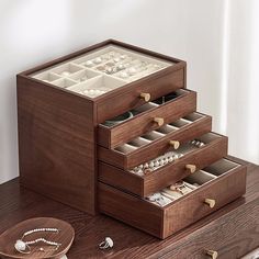 three drawers are open on a wooden table with jewelry in the bottom drawer and one is empty