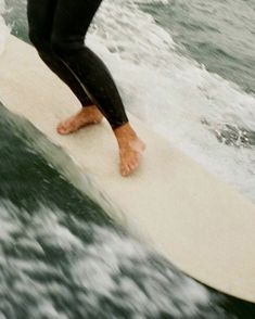 a person standing on a surfboard in the ocean water with their feet propped up