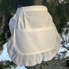 a white apron hanging from a tree in the snow