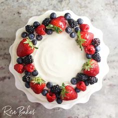 a cake decorated with berries and blueberries on a white plate, top view from above