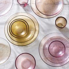 there are many different colored glass plates on the table top, including one with gold rims