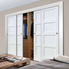 a living room with two doors open to reveal the closet and bed in front of it