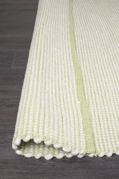 a white and green rug on top of a wooden floor