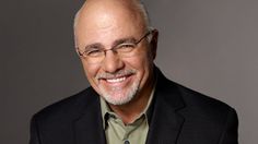 an older man wearing glasses and a suit smiles at the camera while standing in front of a gray background