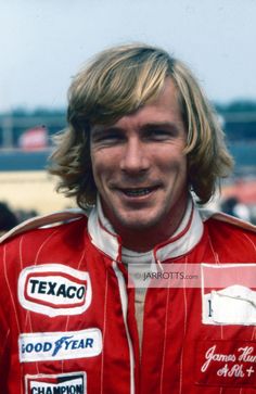 a man with long hair wearing a red racing suit