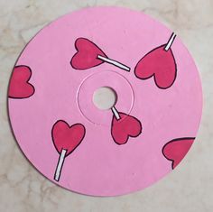 a pink disc with hearts and lollipops on it sitting on a table