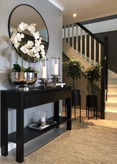 a table with flowers and candles on it in front of a staircase area that has stairs leading up to the second floor