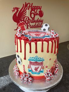 a soccer themed birthday cake with red icing and decorations on the top, sitting on a silver platter