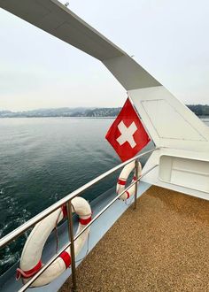 the deck of a boat with life preservers on it's railing and water in the background