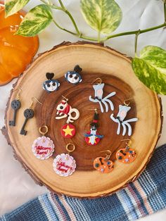 an assortment of earrings sitting on top of a wooden plate next to a potted plant