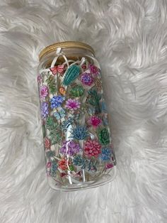 a jar filled with lots of colorful flowers on top of a white fur covered floor