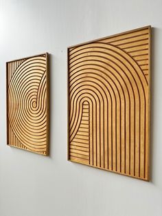 two wooden paintings hanging on the wall next to each other in an office space with white walls