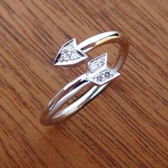 two silver rings with diamonds sitting on top of a wooden table