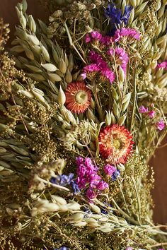 an arrangement of wildflowers and other flowers on a wooden table with wood background