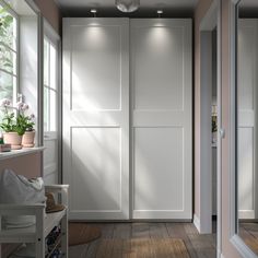 an empty hallway with white closet doors and potted plants in the window sill