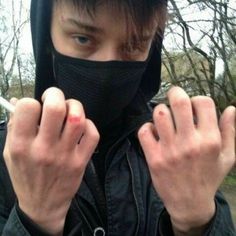 a man wearing a black mask and holding his hands up to the camera with one hand