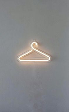 a white neon light hanging from the side of a wall with a hanger on it