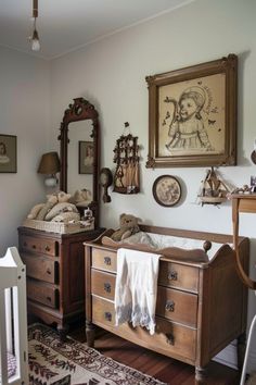 a baby's room with an antique crib, dressers and pictures on the wall