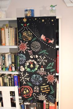 a book shelf filled with lots of books next to a black board covered in christmas decorations