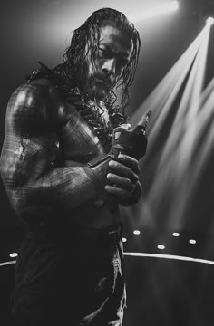 a man with long hair holding a bottle in his hands while standing on a stage