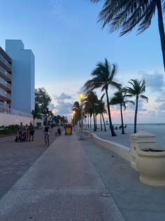 people are riding bikes on the sidewalk near the beach