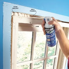 a person spray painting the outside of a window with blue and white paint on it