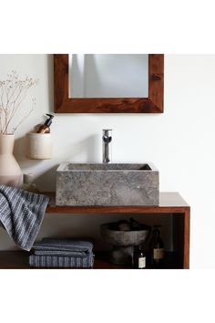 a bathroom sink sitting under a mirror next to a vase