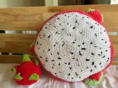 a crocheted strawberry pillow sitting on top of a bed next to a stuffed animal