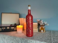 a red bottle sitting on top of a table next to a candle