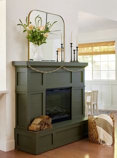 a fireplace in a living room with a mirror above it and flowers on the mantle