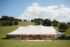 a large white tent set up in the middle of a field with tables and chairs