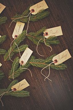 pine branches with name tags on them sitting on a table next to some string and twine