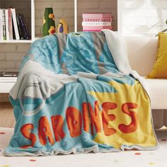 a blanket with the word sardines on it in front of a white couch