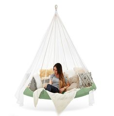 a woman sitting in a hammock with pillows on it