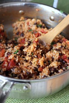 rice and beans are mixed together in a large pot with a wooden spoon on the side