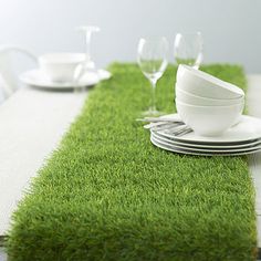 the table is set with white dishes and silverware on green carpeted placemats