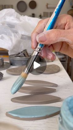 a person holding a paintbrush in their left hand and painting circles on the table