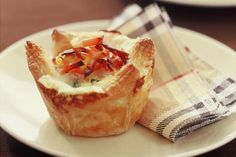 a small pastry on a plate with a checkered napkin next to the cupcake