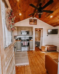 an open kitchen and living room with wood flooring in a small cabin style home