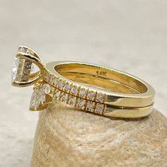 two gold wedding rings sitting on top of a rock next to another ring with diamonds