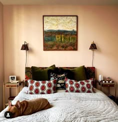 a dog laying on top of a bed in a room with pink walls and pillows